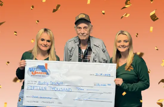 Two West Orange Roofing crewmembers standing with a man who received a free roof from the company