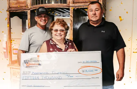 A West Orange Roofing team member standing with a couple who received a free roof.