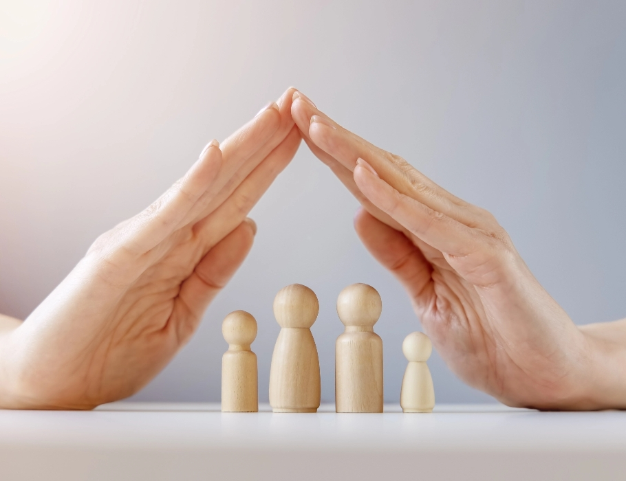 An image with two hands over four wooden figures shaped like people