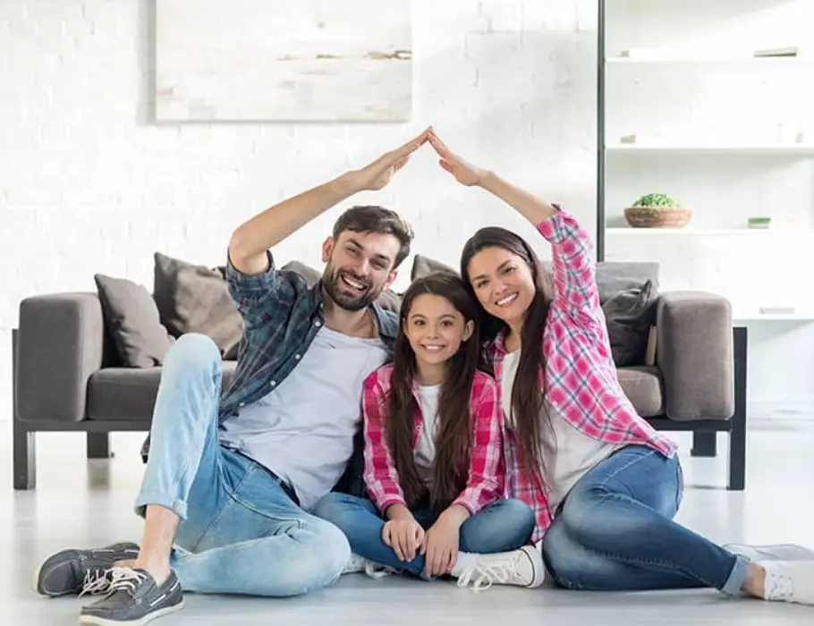 A happy couple sitting on the floor of their home with their daughter